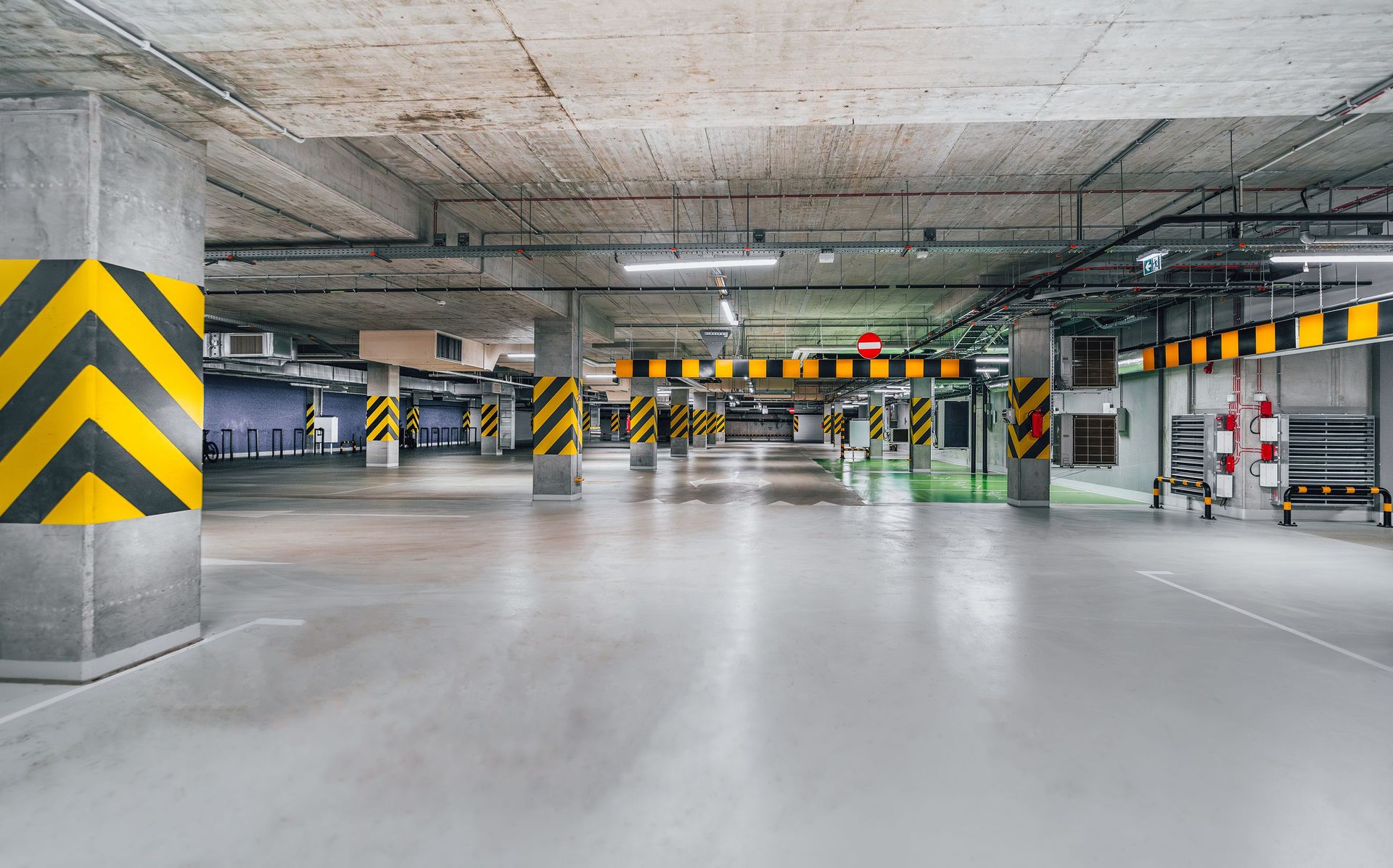 Wide-angle view of an empty underground parking garage featuring concrete columns and safety markers.