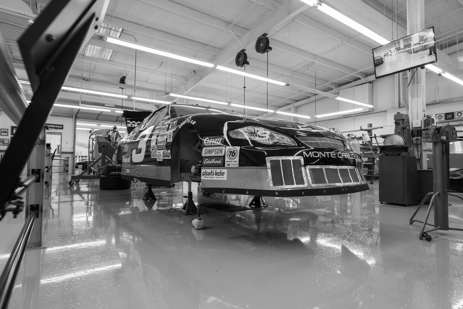 Monochrome image of a Monte Carlo race car in a professional garage setting.